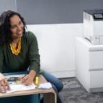 Xerox® VersaLink® C620 Drucker in einem Büro Lächelnde Frau in einem Büro neben dem Xerox® VersaLink® C620 Farbdrucker