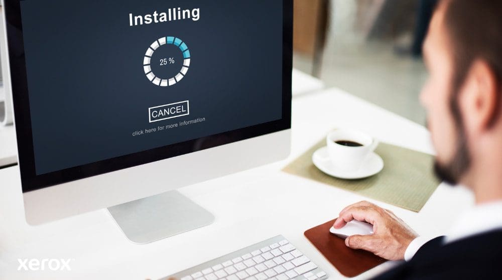 Xerox® Smart Start: Einfache und schnelle Installation Eine Nahaufnahme eines Computermonitors mit einem Fortschrittsbalken „Installation läuft“ bei 25 %, mit der Hand einer Person auf einer Computermaus neben einer Kaffeetasse, was die einfache Einrichtung der Software veranschaulicht.